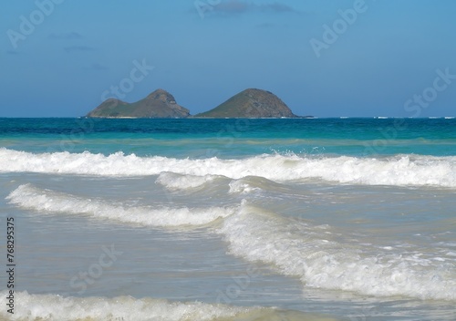 looking toward moku iki island across the azure waters and surf of the pacific ocean, from the bellows field beach park on the windward coast of oahu, hawaii © Nina