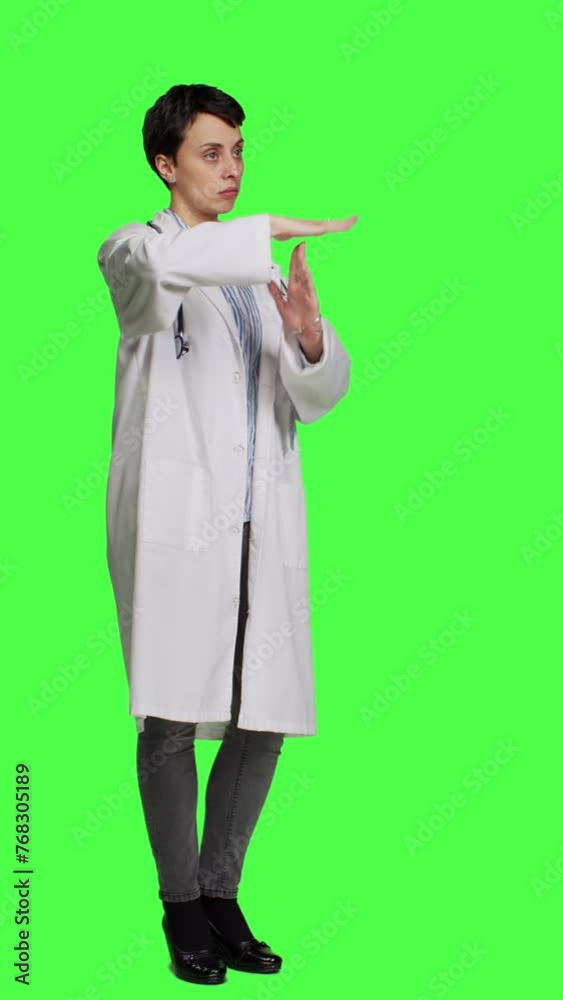 Side view Woman physician doing timeout gesture against greenscreen backdrop, asking for a work break after multiple examinations. Doctor showing pause or stop symbol, feeling tired. Camera A. Side view Woman physician doing timeout gesture against greenscreen backdrop, asking for a work break after multiple examinations. Doctor showing pause or stop symbol, feeling tired. Camera A.