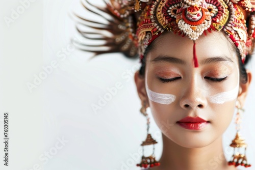 Tranquil portrait of a Balinese dancer with white makeup and a detailed, regal headdress