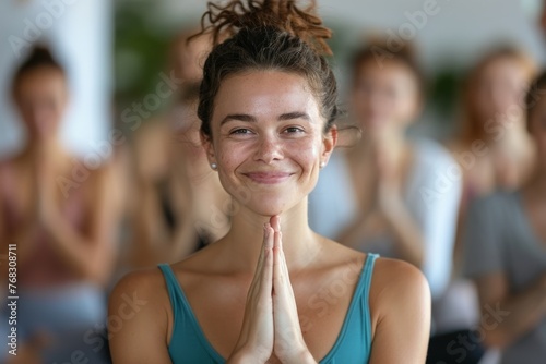Serene young woman with hands in namaste, enjoying a moment of peace in a group yoga class