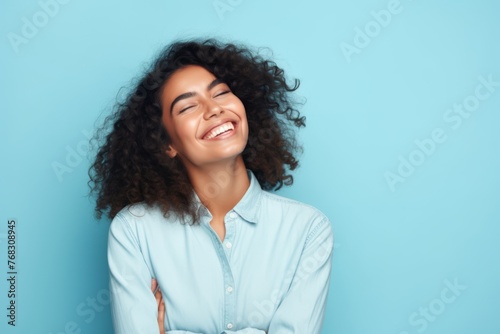 Portrait of young beautiful african american woman with long curly hair smiling on blue background