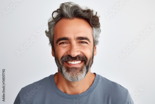 Positive delighted man looking at camera and smiling while standing against grey background
