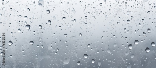 A close up of water droplets on a window, created by the atmospheric event of drizzle. The grey liquid reflects the moisture of the precipitation