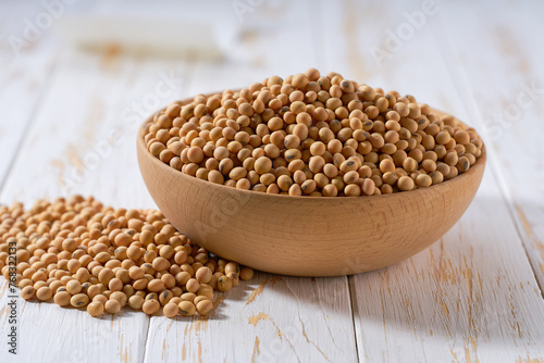 Organic soybeans in a wooden bowl on a white wooden table.