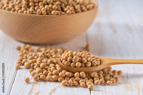 wooden spoon with raw soybeans on a light table, selective focus.