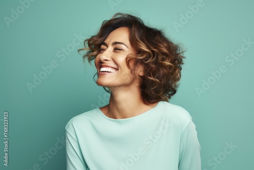 Portrait of happy smiling young woman with curly hairstyle over blue background