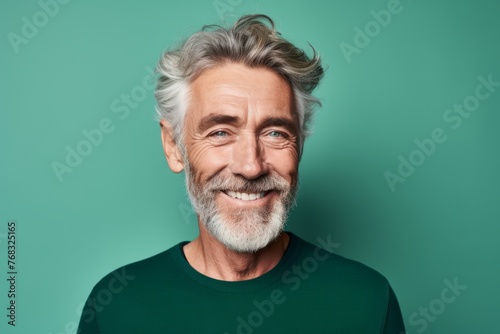 Portrait of a smiling senior man looking at camera isolated over green background © Chacmool