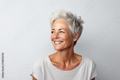 Portrait of a happy senior woman with grey hair against grey background