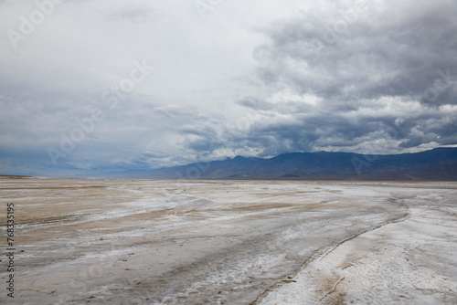 Salt flats at badwater basin in Death Valley with distant mountains under a gloomy sky