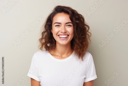 Portrait of a happy young woman with curly hair against grey background