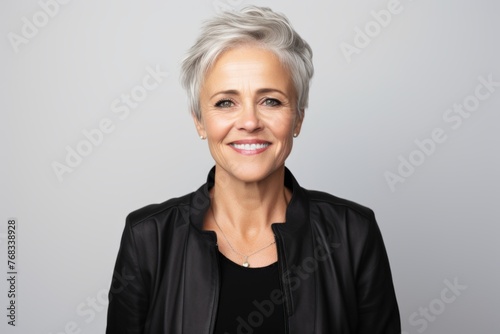 Portrait of happy senior business woman in black jacket over grey background