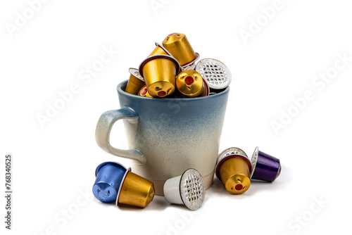 A colorful pile of used coffee maker pods in a coffee cup isolated on white