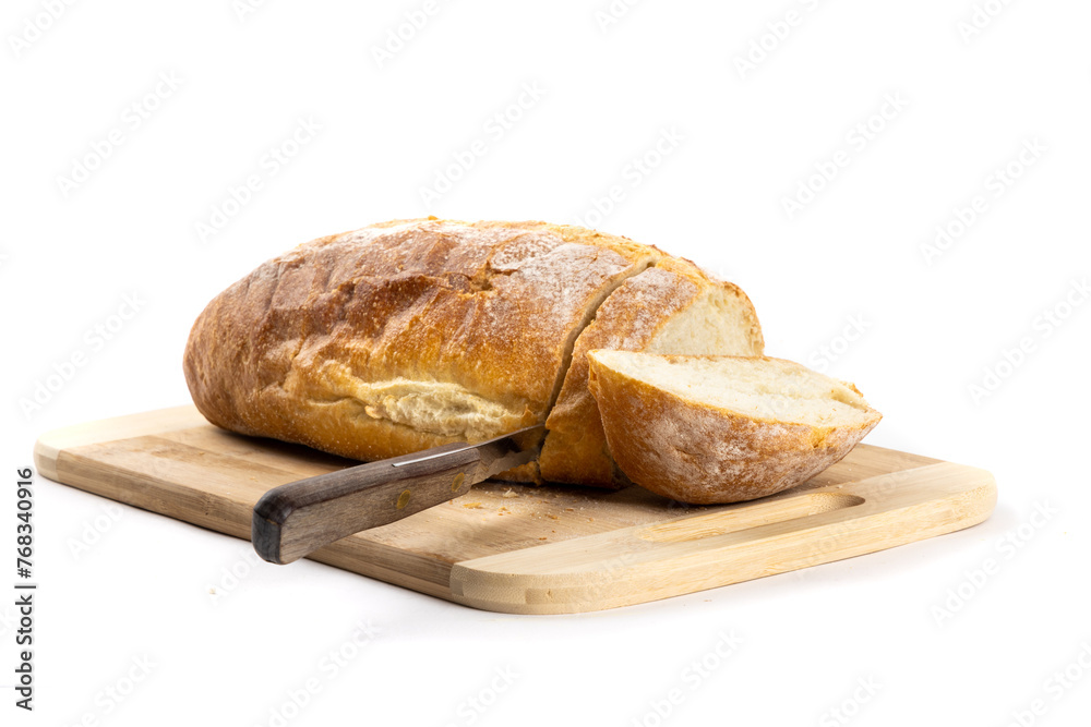 A loaf of crusty bread with the heel end cut off on a wooden cutting board showing the serrated knife used isolated on white
