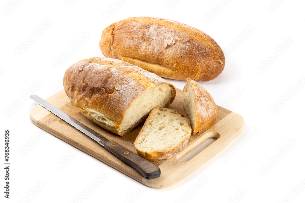 A whole loaf of artisanal crusty bread with slice cut off on a wooden cutting board  and another loaf in the background isolated on white