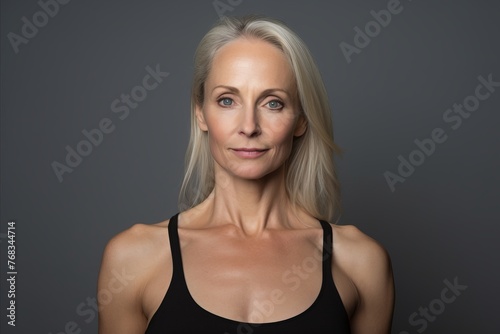 Portrait of beautiful mature woman looking at camera with serious expression, over grey background