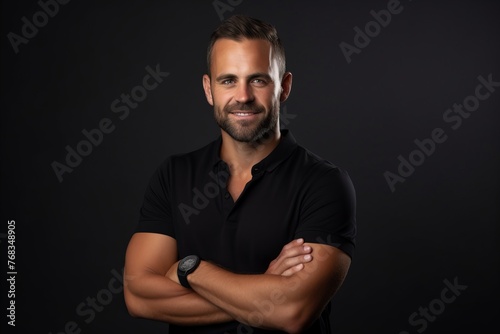 Portrait of a handsome young man with crossed arms on black background