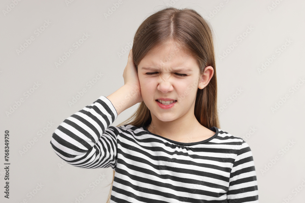 Hearing problem. Little girl suffering from ear pain on grey background Hearing problem. Little girl suffering from ear pain on grey background
