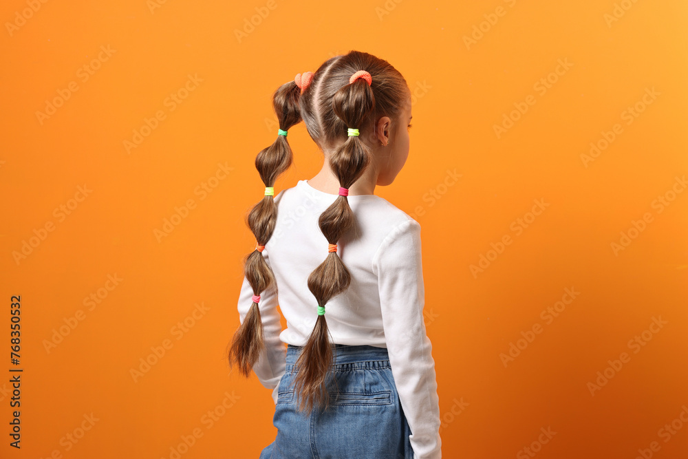 Fototapeta premium Little girl with beautiful hairstyle on orange background, back view