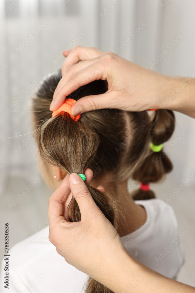 Naklejka premium Professional stylist braiding girl's hair indoors, closeup
