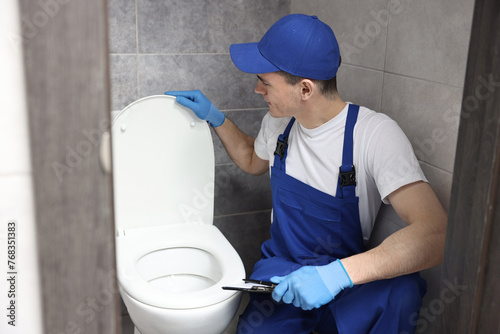 Plumber examining toilet bowl in water closet