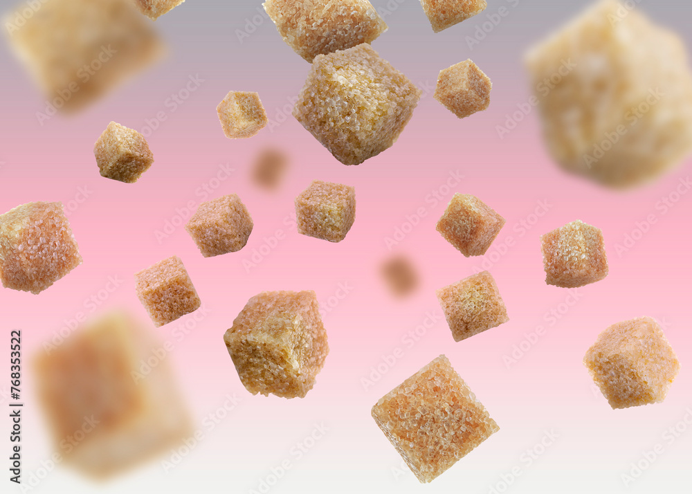 Brown cane sugar cubes falling on color gradient background Brown cane sugar cubes falling on color gradient background
