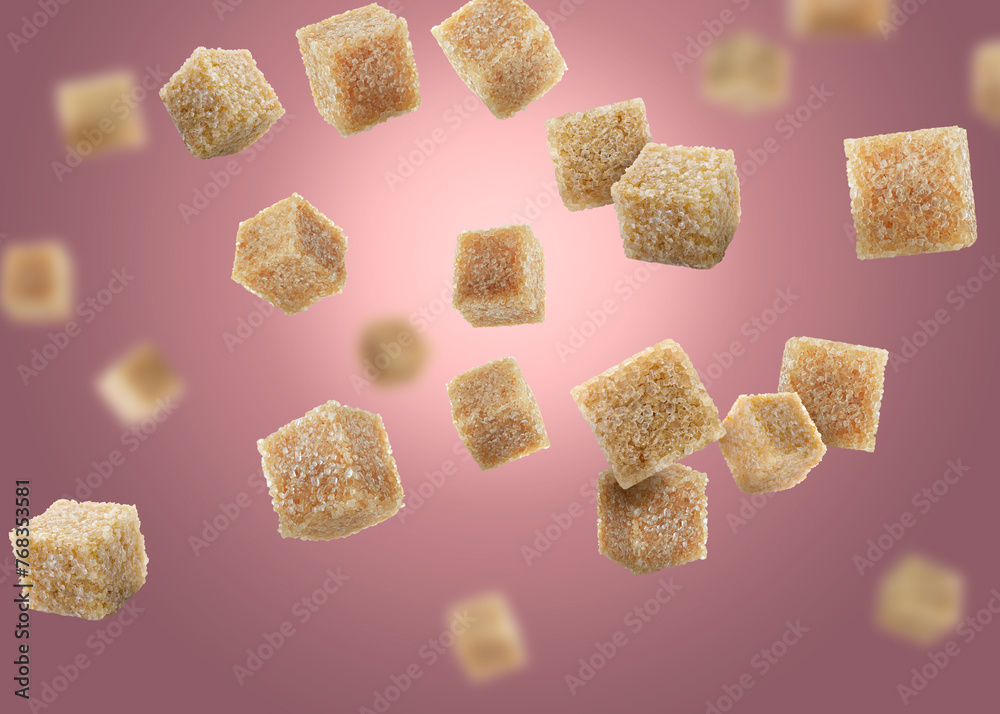 Brown cane sugar cubes falling on dark pink gradient background Brown cane sugar cubes falling on dark pink gradient background