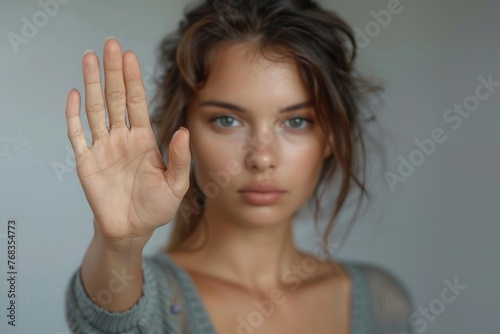 Atmospheric portrait of a woman with wavy hair raising her hand in a stopping motion
