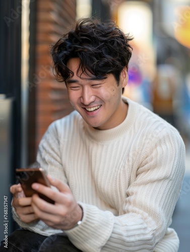 Man laughing at smartphone outdoors - Smiling man thoroughly amused by content on his smartphone while outdoors