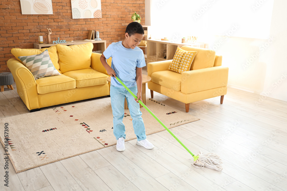 Cute African-American boy mopping floor in living room - obrazy, fototapety, plakaty 