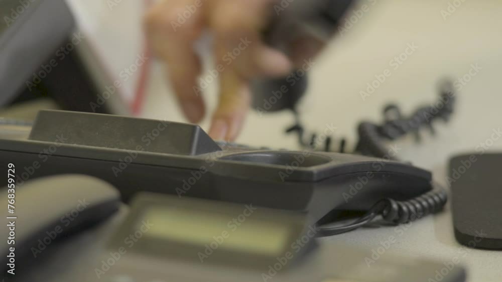 Hand picking up a black office phone, dialing swiftly, blurred background Hand picking up a black office phone, dialing swiftly, blurred background