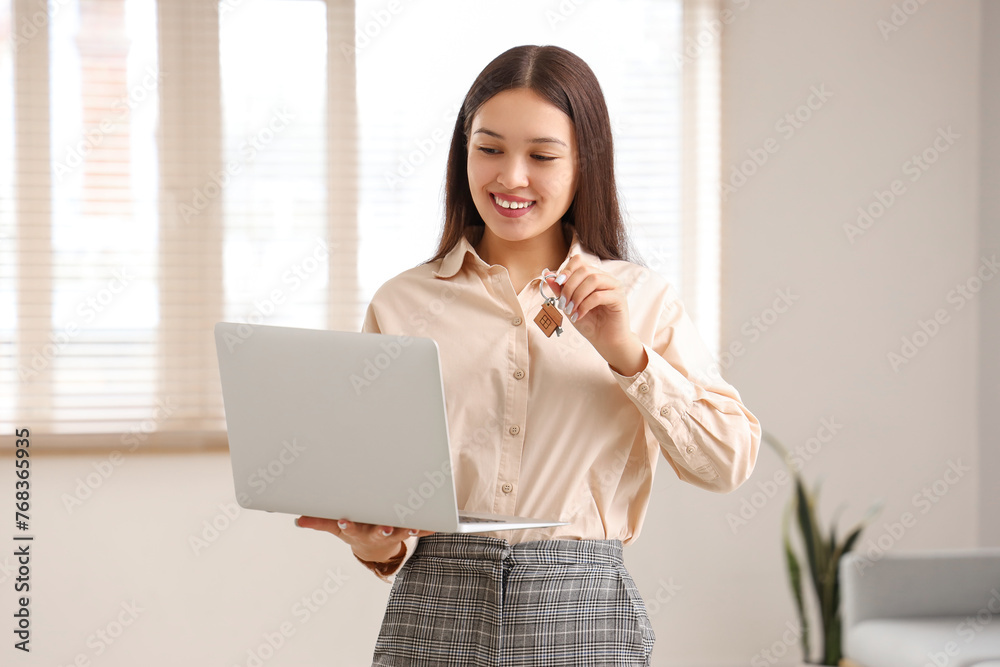 Asian real estate agent with laptop and key in apartment