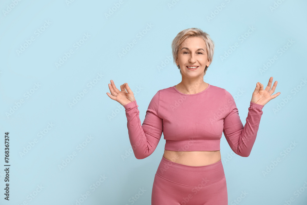 Portrait of meditating mature woman on blue background Portrait of meditating mature woman on blue background