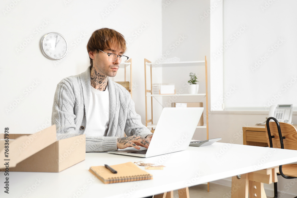 Young online store seller working with laptop at table in warehouse Young online store seller working with laptop at table in warehouse