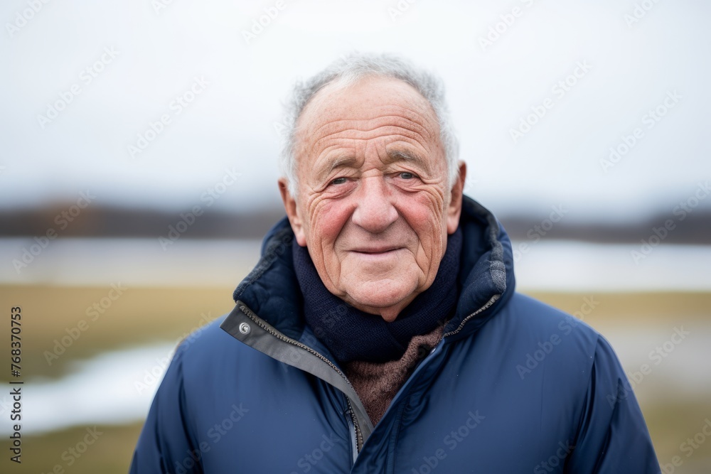 Portrait of an elderly man in a blue jacket on the nature