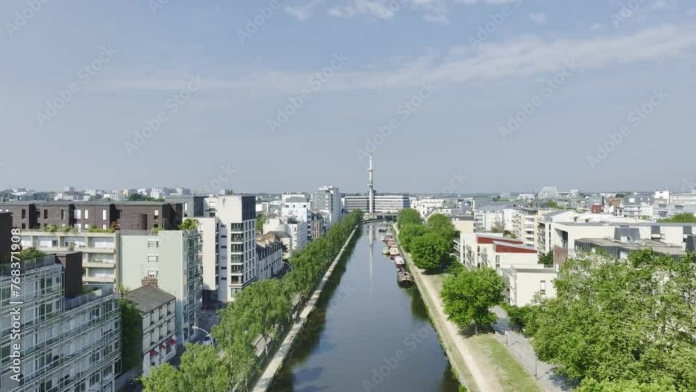 Aerial travelling drone shot of Rennes, Bretagne, France, quai de la Prévalaye, le Mabilay. Scenic cityscape with sunny blue sky, river, quays, green trees, architecture, bird flying.