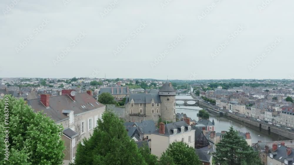 Reveal aerial drone shot of Laval castle from behind a green tree, in Mayenne, France. Quays of the Mayenne river. Tourism sightseeing location. Reveal aerial drone shot of Laval castle from behind a green tree, in Mayenne, France. Quays of the Mayenne river. Tourism sightseeing location.