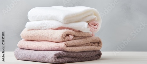 A stack of linens made from natural materials, possibly wood or animal products, rests on a table. Among the pile are towels in shades of magenta and furlike textures