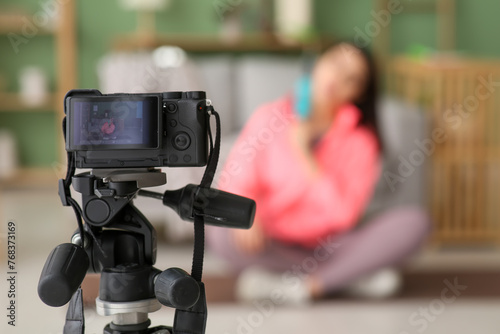 Female blogger with massage roller recording sports video on camera screen at home, closeup