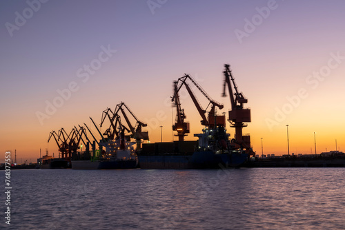 Gantry crane and cargo ship in the evening