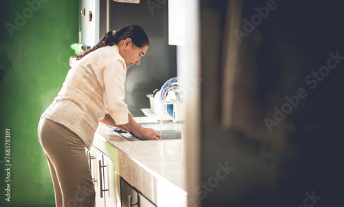 Una mujer mayor organizando la cocina de la casa 