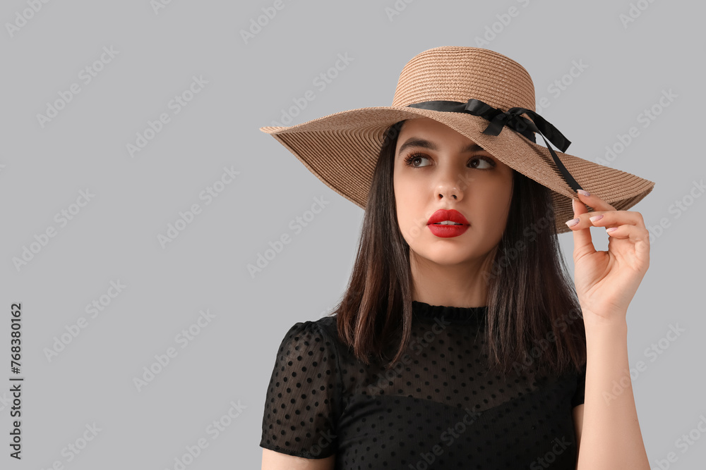 Beautiful young woman in hat with red lips on grey background Beautiful young woman in hat with red lips on grey background
