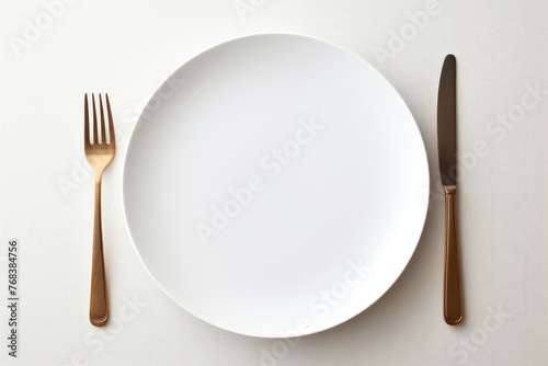 A clean white empty plate with a single fork and knife, epitomizing fine dining with copy space