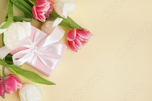 Gift box and beautiful tulips on yellow background