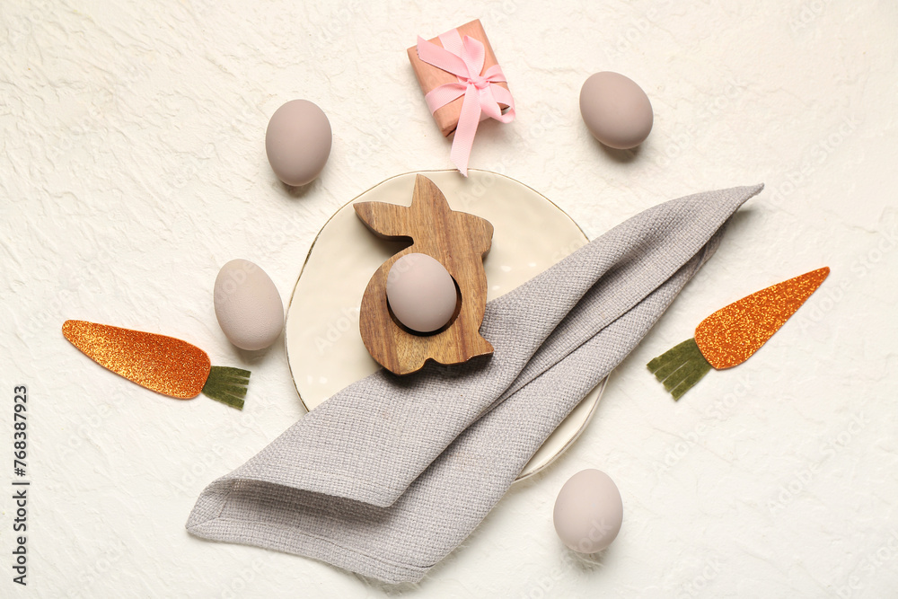 Easter eggs with carrots and gift box on white background