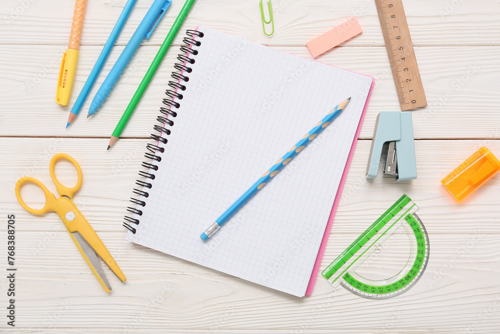Notebook with scissors and stapler on white wooden background. Top view Notebook with scissors and stapler on white wooden background. Top view