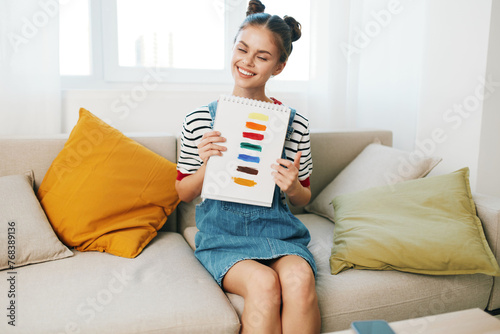 Happy Teenage Artist Creating Artwork at Home: A Cute Girl Paints on Sofa