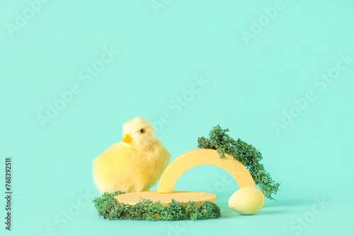 Decorative podiums with Easter egg and chick on turquoise background