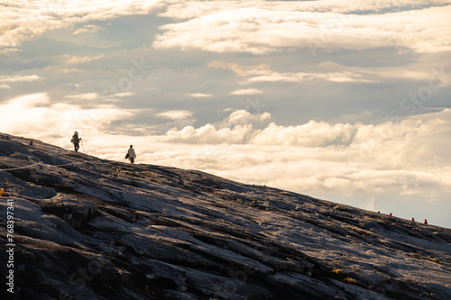 Tourist walking on granite plateau on Mt.Kinabalu during sunrise. Mt Kinabalu is one of the highest mountain in South East Asia.