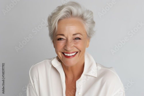 Portrait of a happy senior woman smiling at the camera against grey background