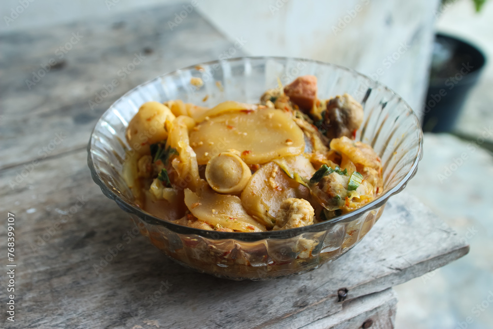 Seblak is a typical Indonesian dish with a savory and spicy taste. cooked with vegetables, sausage, eggs, chicken feet, seafood and processed beef. a bowl of seblak on a wooden table. Seblak is a typical Indonesian dish with a savory and spicy taste. cooked with vegetables, sausage, eggs, chicken feet, seafood and processed beef. a bowl of seblak on a wooden table.